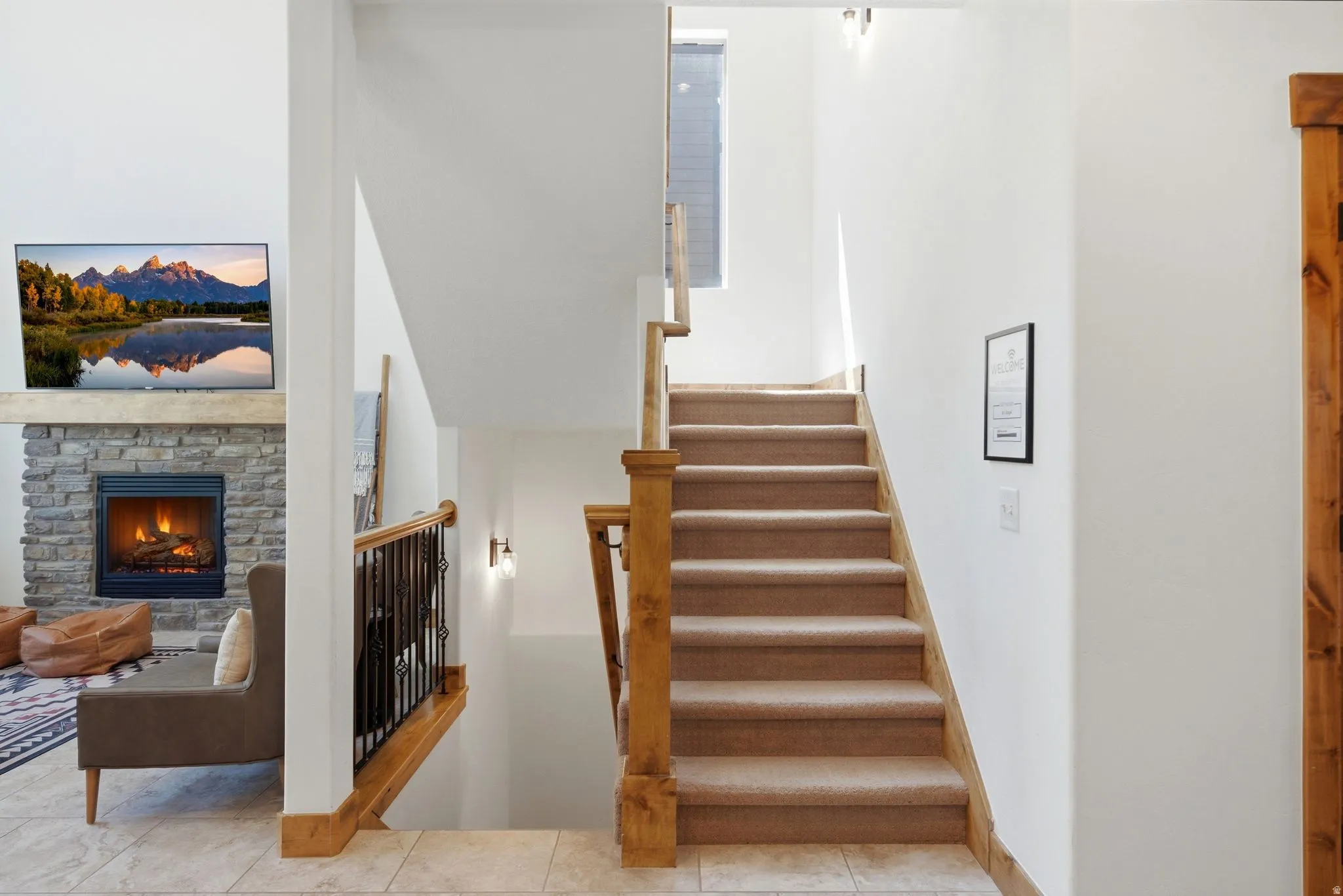 Carpeted staircase with wood railings and wrought iron balusters