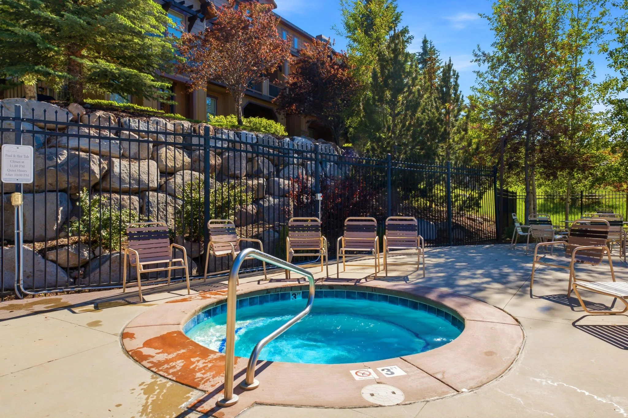 Circular spa with integrated steps and a stainless steel handrail, surrounded by concrete decking
