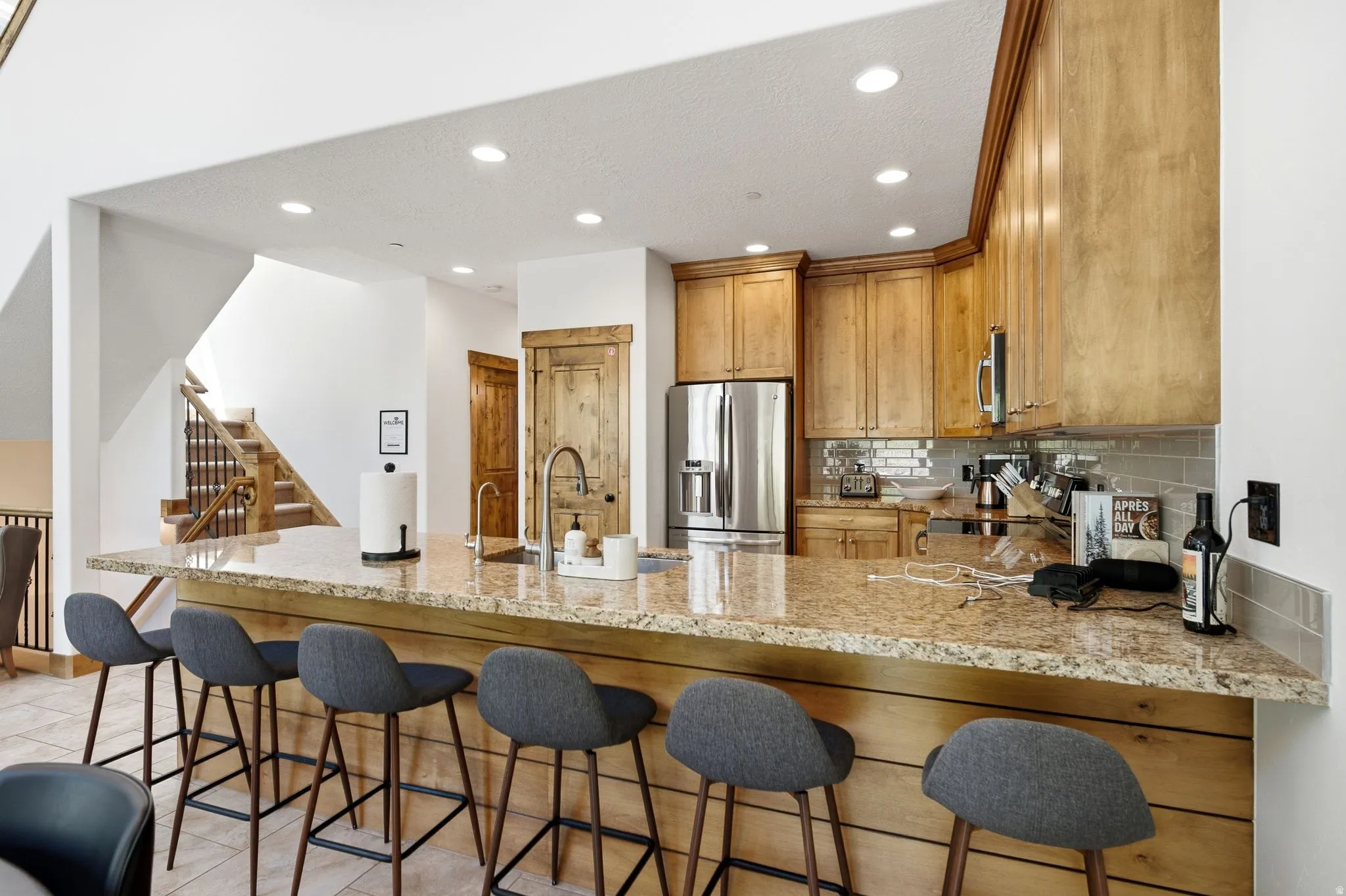 Kitchen island with a light-toned stone countertop and wood-finish paneling