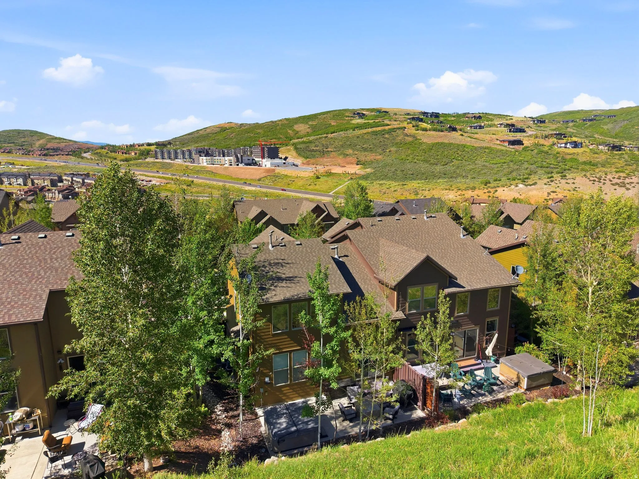 Multi-level residence featuring a brown shingle roof and dark-toned siding