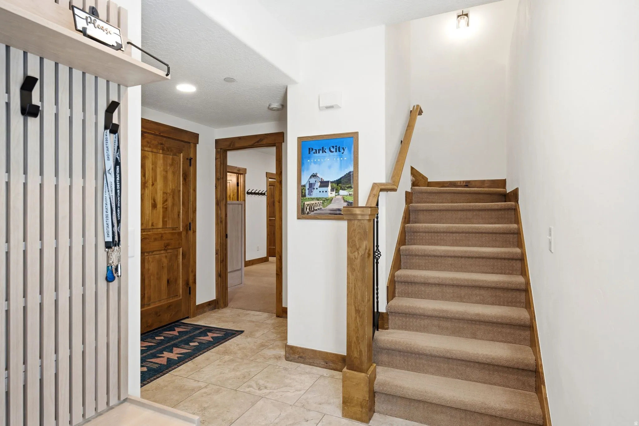 Entryway featuring a carpeted staircase with wood-finish railing and balusters