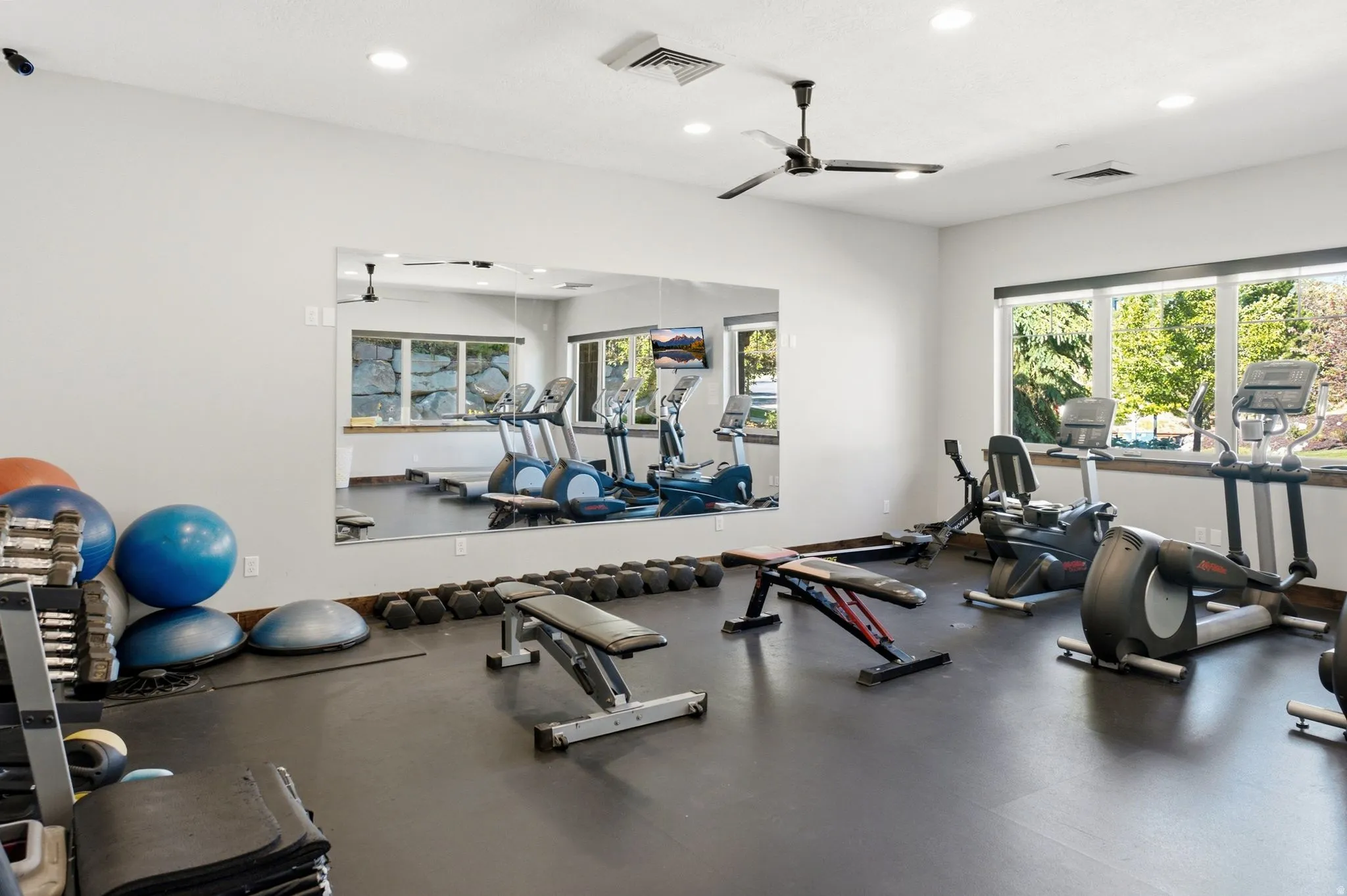 Dedicated fitness space featuring a rubberized floor, full-wall mirror, recessed lighting, and a ceiling fan