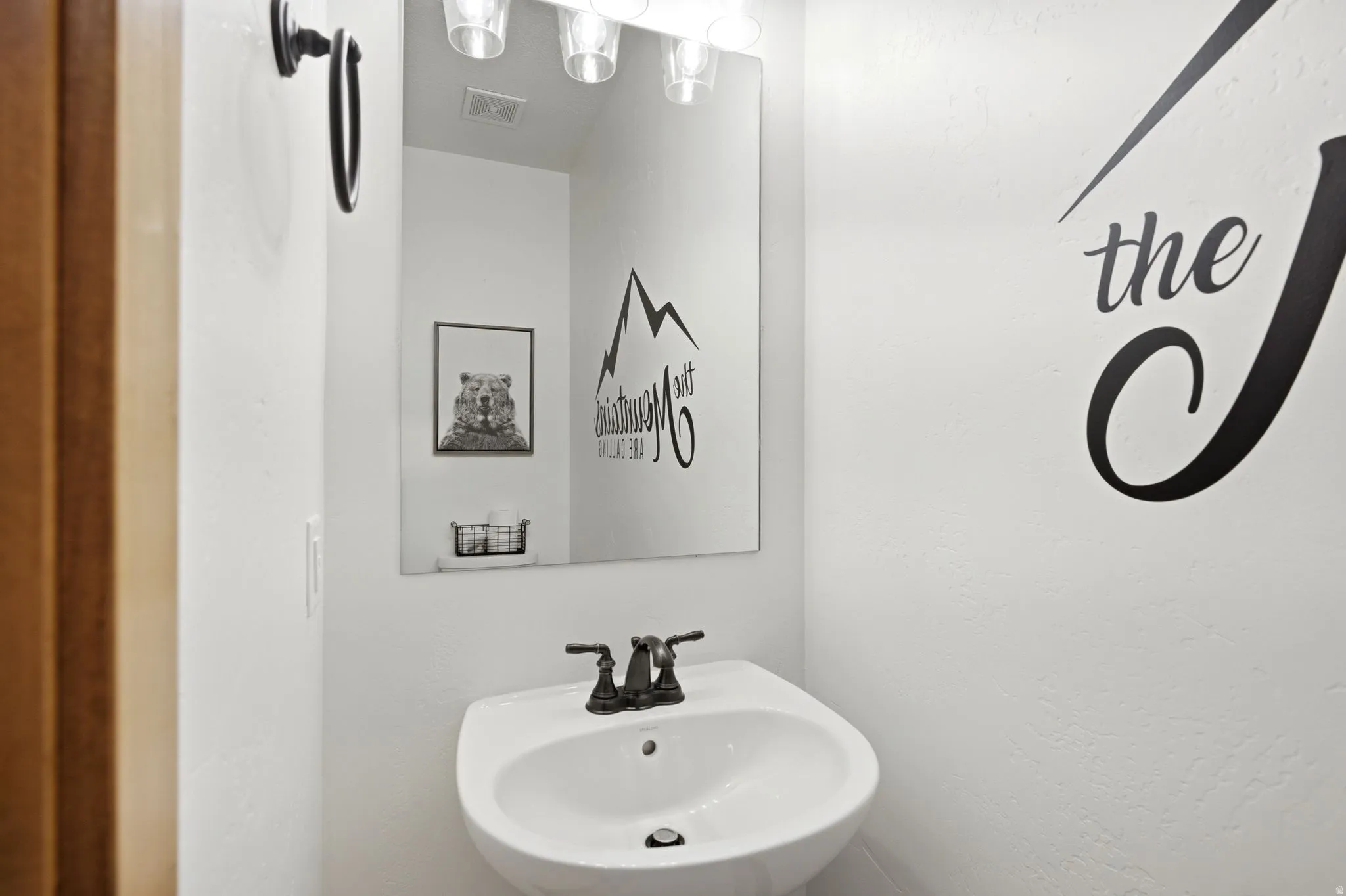 White pedestal sink with a dark bronze-finish faucet