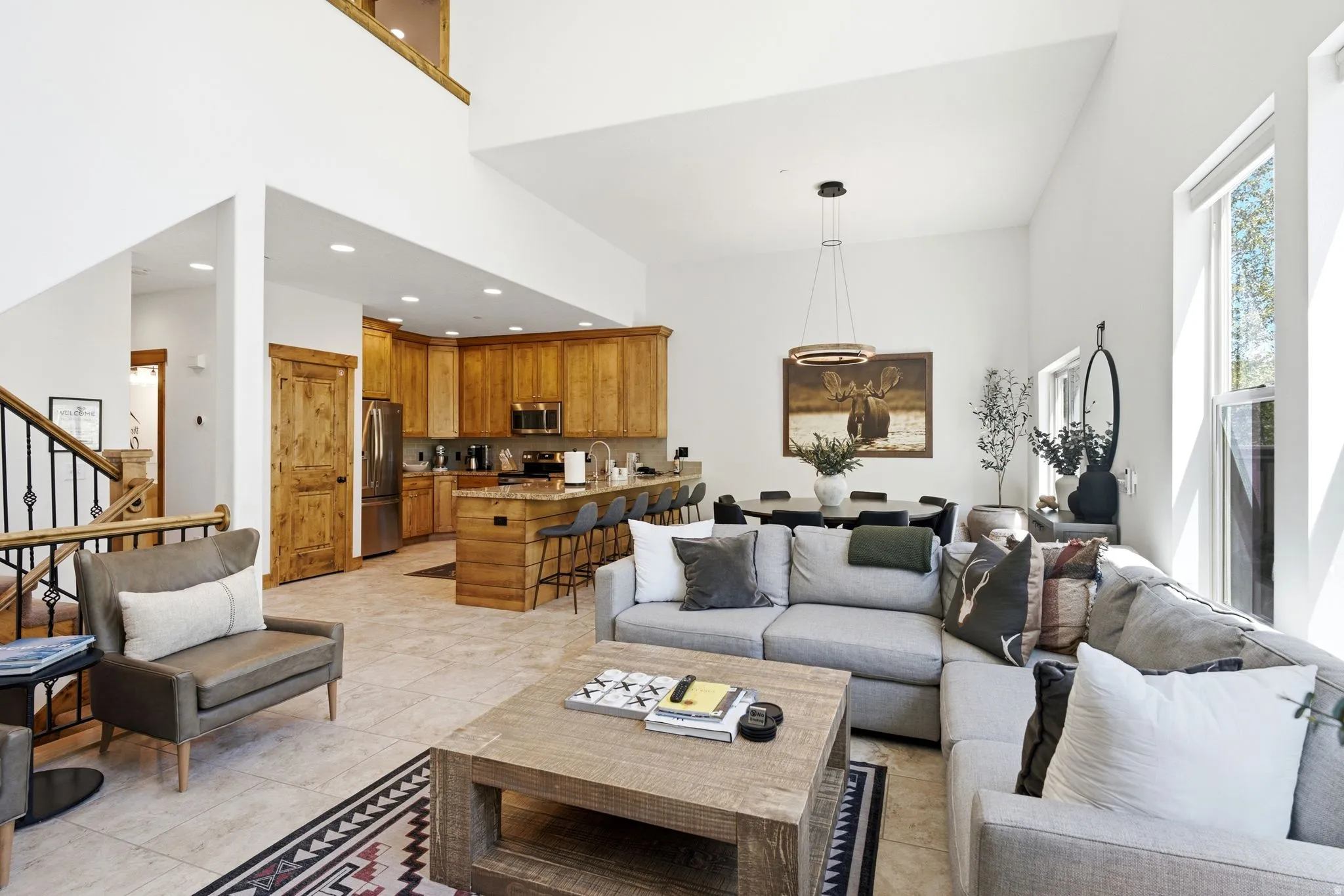 Open-concept living space featuring high ceilings, light tile flooring, and abundant natural light from multiple windows