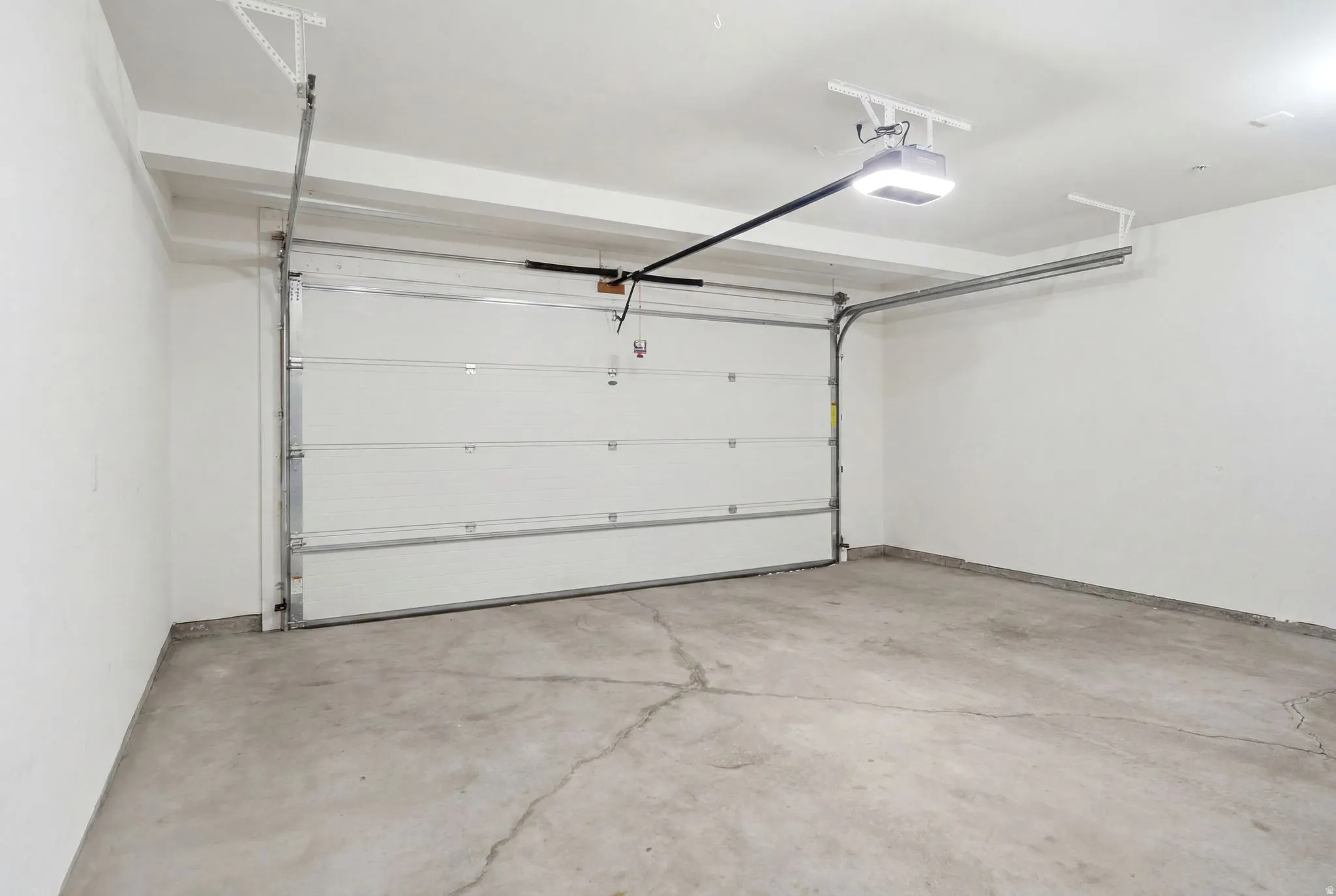 Spacious garage featuring a white overhead door, concrete flooring, and an automatic garage door opener