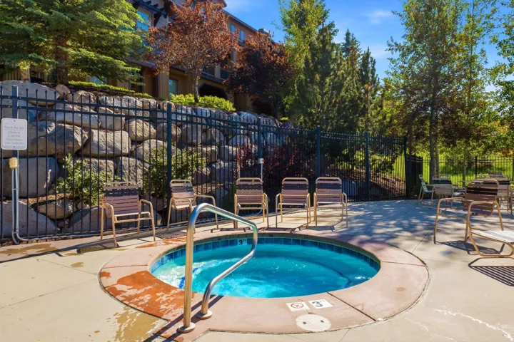 Circular spa with integrated steps and a stainless steel handrail, surrounded by concrete decking