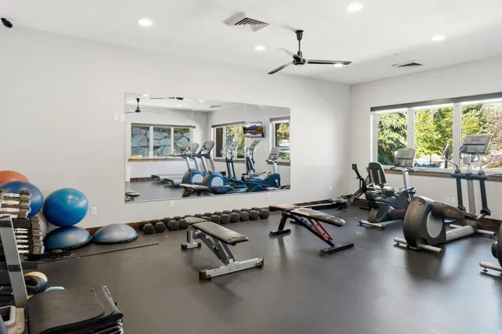Dedicated fitness space featuring a rubberized floor, full-wall mirror, recessed lighting, and a ceiling fan