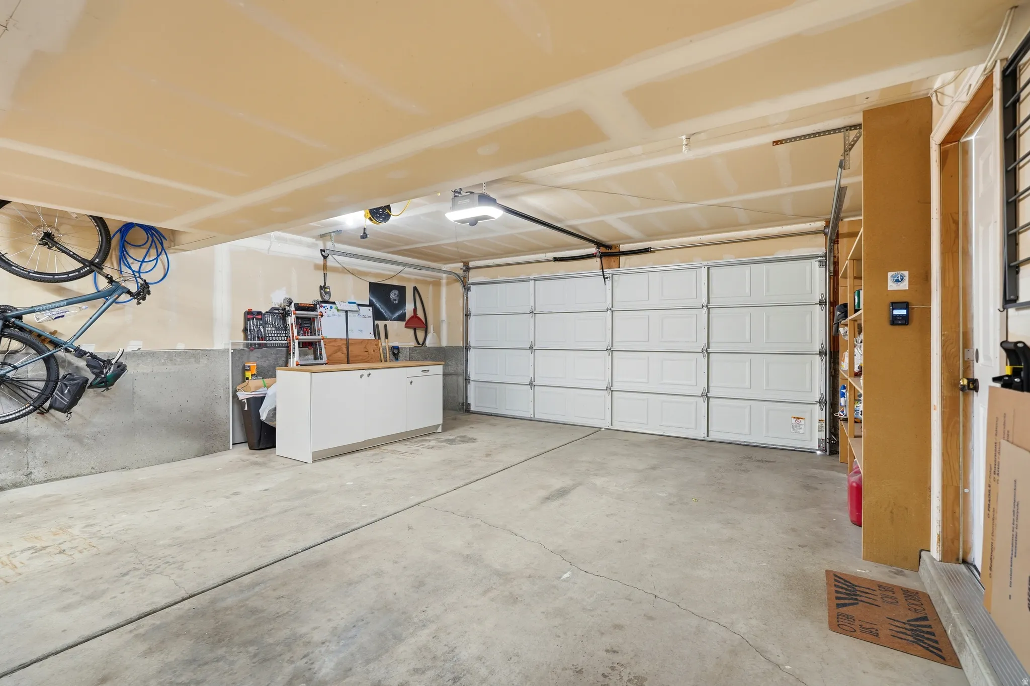 Spacious garage featuring a concrete floor, overhead lighting, and a white paneled garage door
