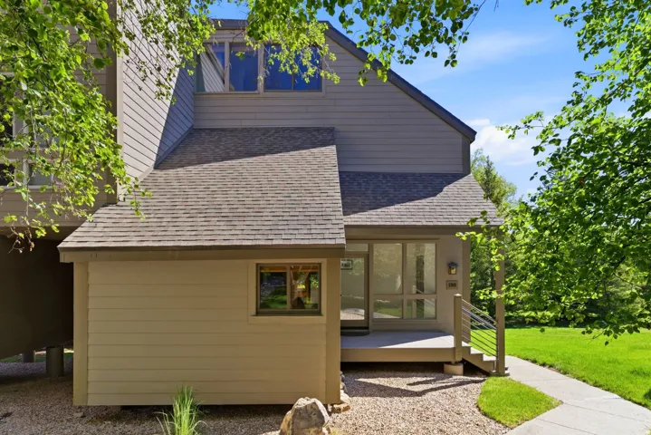 Multi-level exterior with neutral siding, a covered entrance, contemporary railings, and an asphalt shingle roof