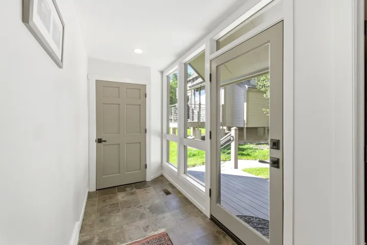 Entryway featuring large glass panel door, side windows, recessed lighting, and slate-look tile flooring