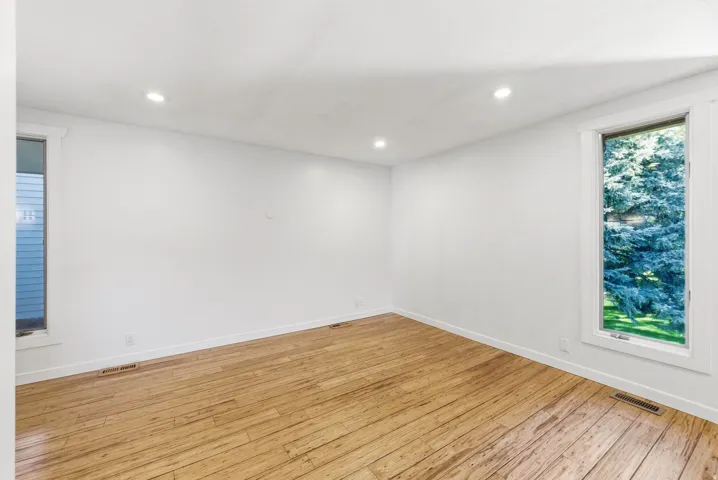 Bright room featuring wood-finish flooring, recessed lighting, and white trim