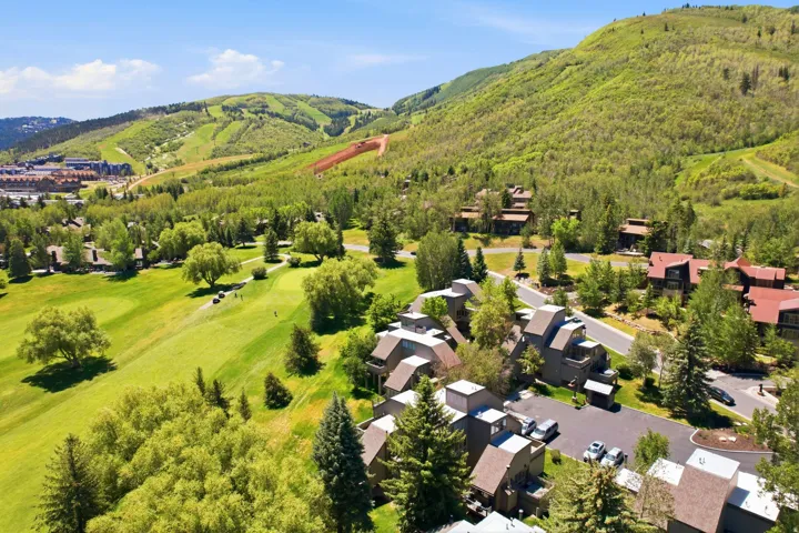 Mountain community featuring multi-story residences, paved roadways, mature evergreen trees, and a manicured golf course