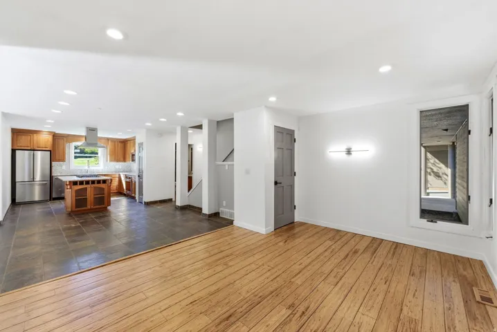 Open-concept living area with wood-finish flooring transitioning to large format tile