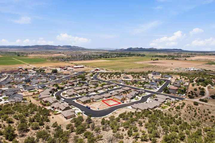 Aerial perspective of a developed residential neighborhood featuring a vacant lot outlined in red