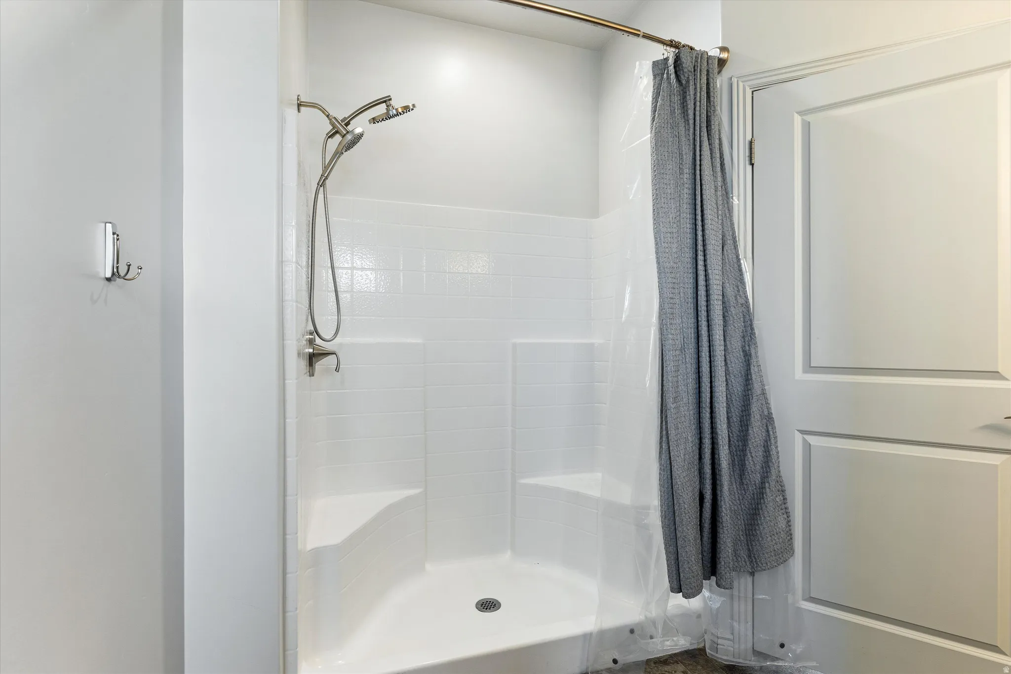 Shower stall featuring white subway-style tile, built-in seating, brushed nickel fixtures, and a shower head with an attached sprayer