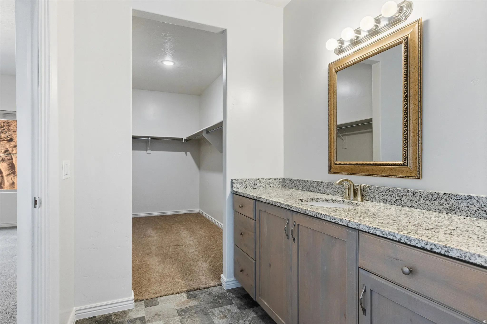 Vanity with a granite-style countertop, undermount sink, and wood-finish cabinetry