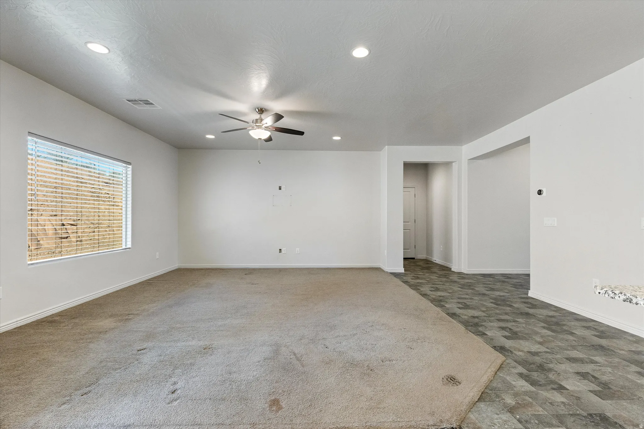 Spacious room featuring a large window, recessed lighting, and a ceiling fan