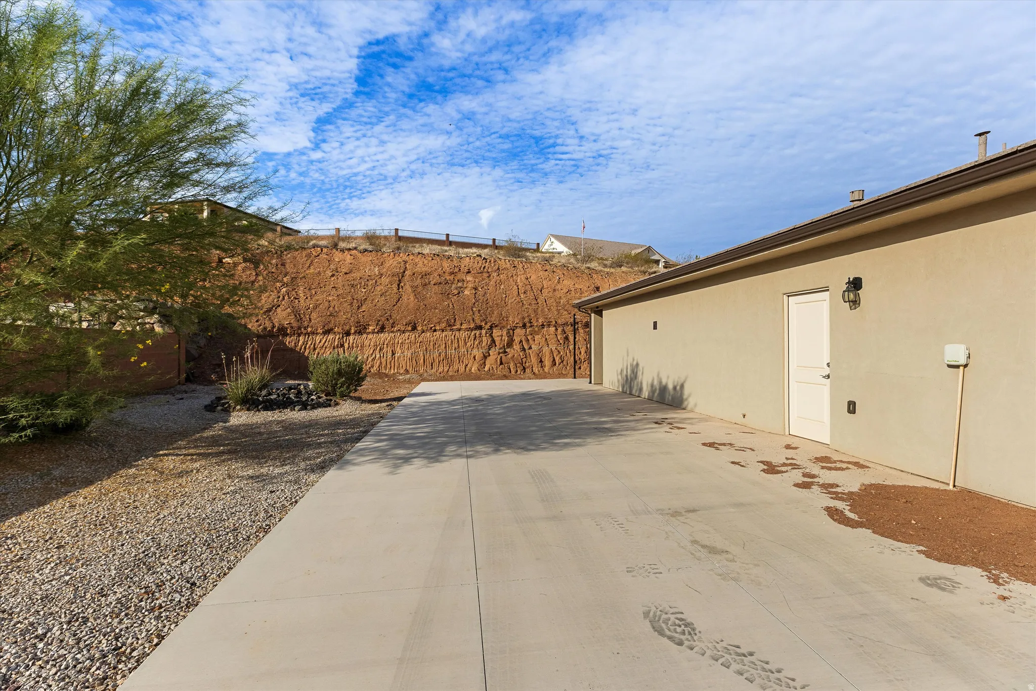 Expansive concrete driveway alongside a stucco building with a side entry door