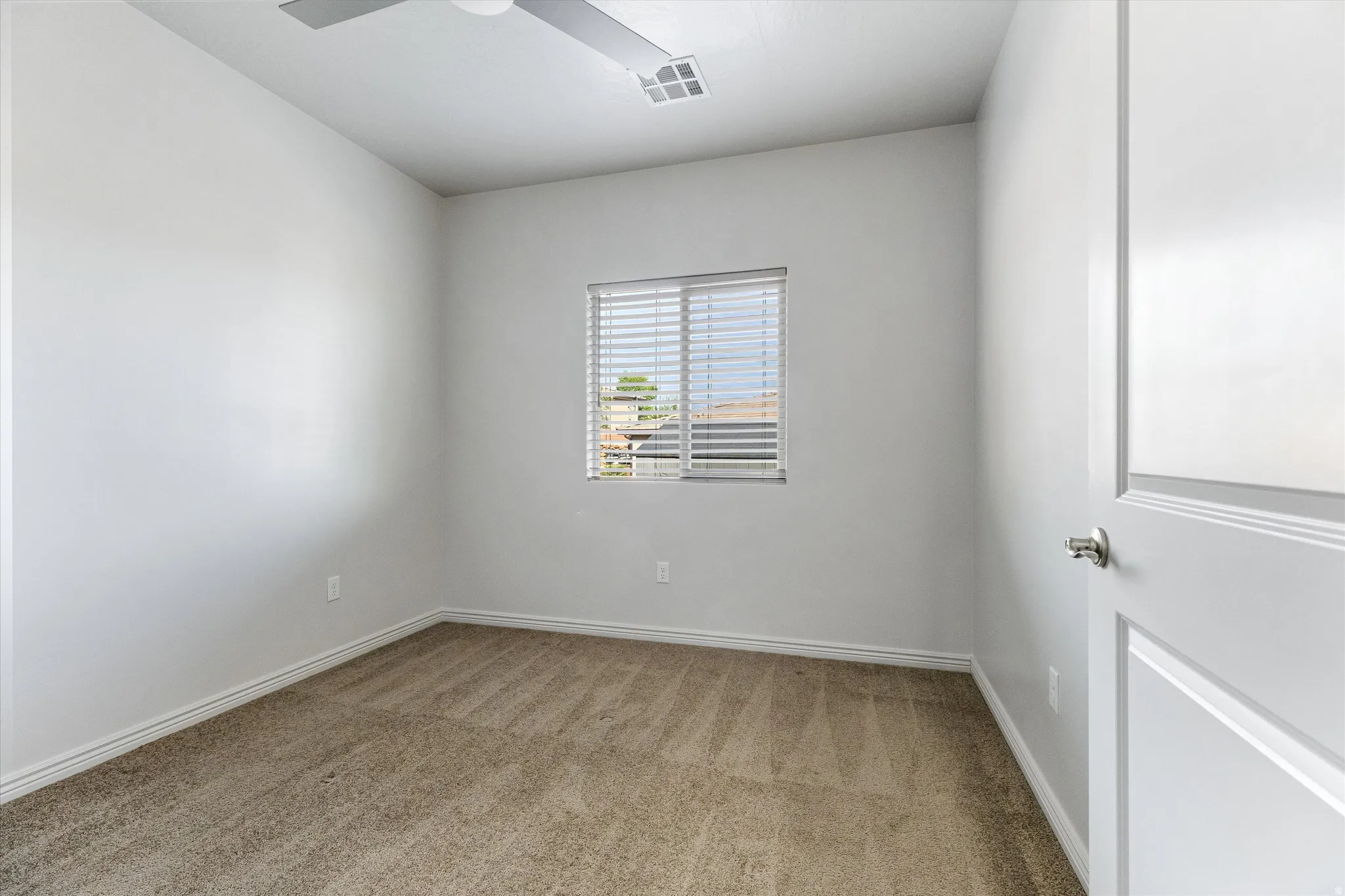 Room featuring light neutral wall paint, textured carpeting, and a window with horizontal blinds