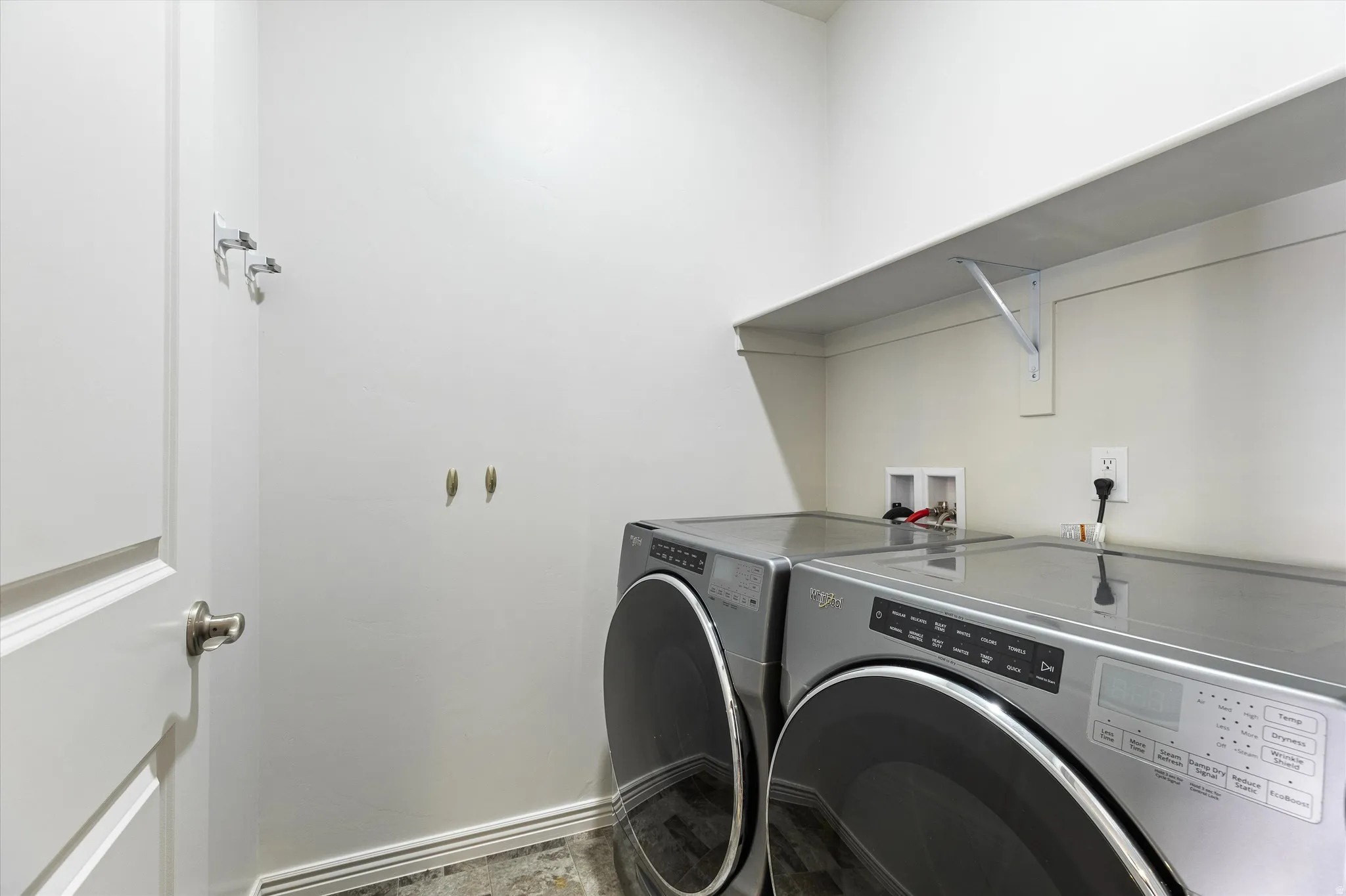 Dedicated laundry space featuring a built-in shelf, neutral wall tones, and dark wood-finish flooring