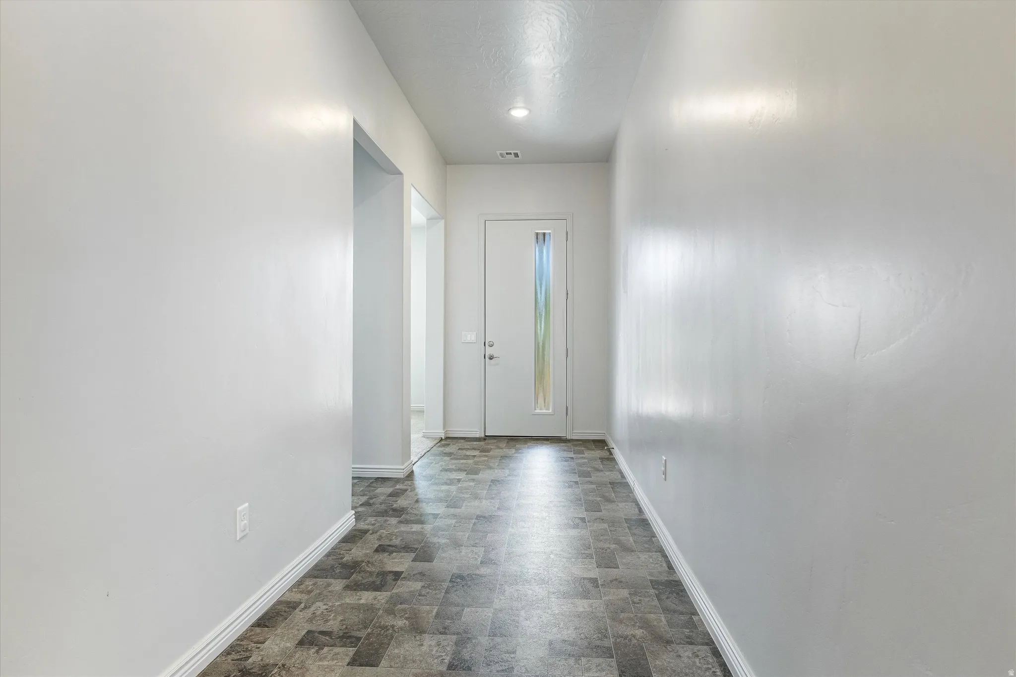Entryway featuring patterned tile flooring, a recessed ceiling light, and a white entry door with an etched glass panel