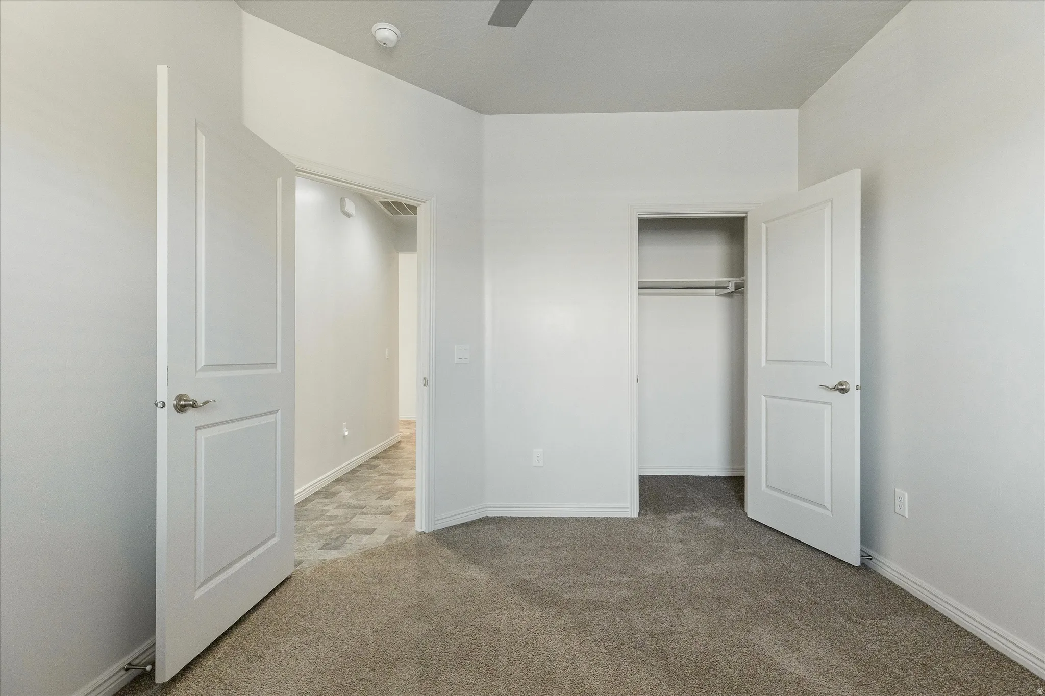 Carpeted room with white walls, a built-in closet with hanging rod, and white paneled doors