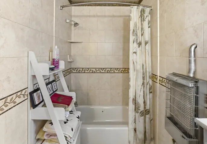 Tub-shower combination featuring a curved shower rod and tiled surround