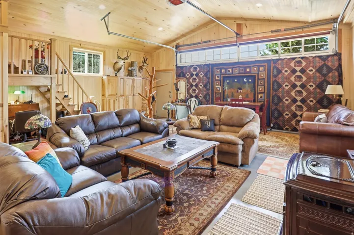 Spacious interior room featuring light wood paneling, a vaulted ceiling, and concrete flooring