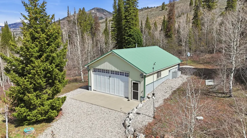 Freestanding structure featuring a green metal roof and light-colored siding