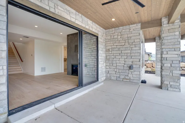 Expansive outdoor living area featuring a stone accent wall, wood-finish ceiling, and concrete patio