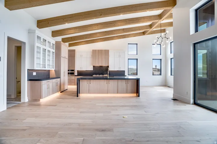 Open-concept living space with a vaulted ceiling featuring exposed wood beams