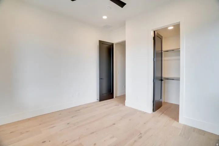 Bright interior space featuring light wood-finish flooring, white walls, and dark-paneled doors