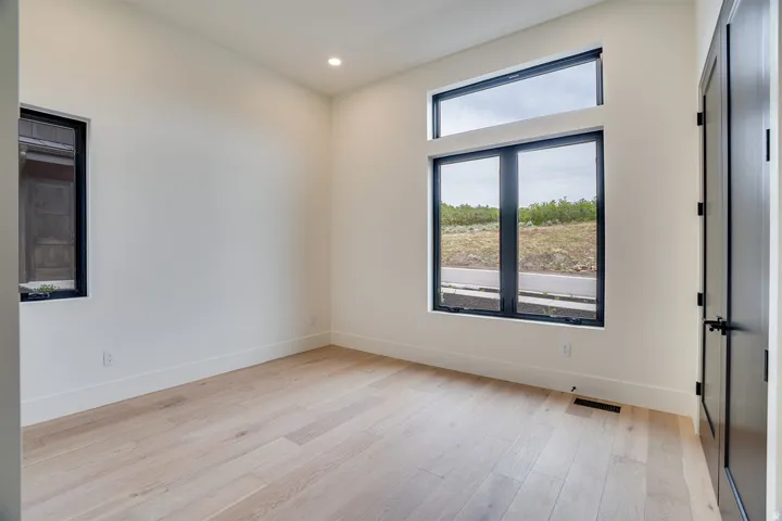 Light-filled room featuring a large transom window, a secondary black-framed window, recessed ceiling lighting, and light wood-finish flooring