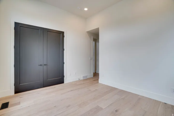 Double black doors with contrasting white trim, recessed lighting, and light wood-finish flooring