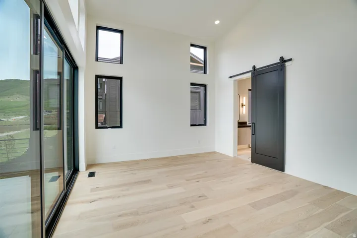 Spacious room featuring light wood-finish flooring, vaulted ceilings, and a large sliding glass door