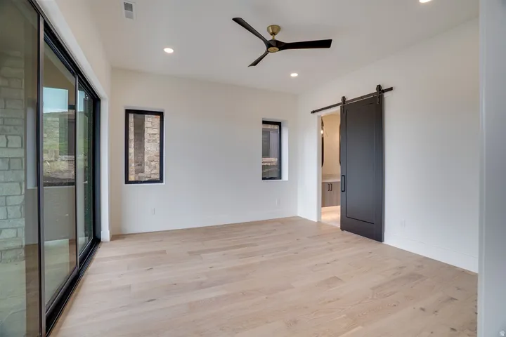 Spacious room with light wood-finish flooring, recessed lighting, and a modern ceiling fan