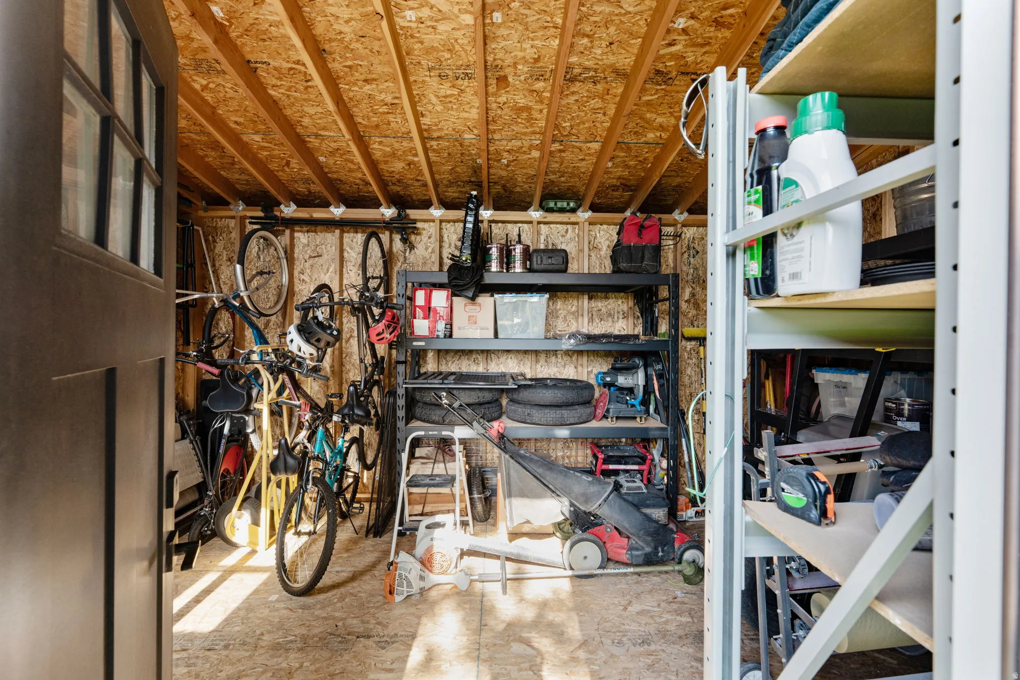 Utility shed featuring exposed wood-finish walls and ceiling, a panel door with windowpanes, and ample space for storage