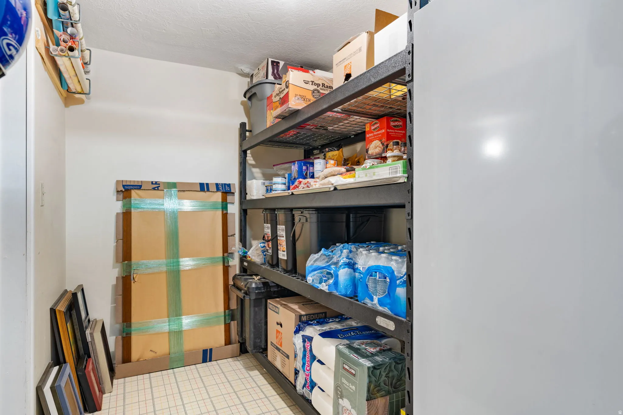 Dedicated storage area featuring utility shelving, a built-in overhead storage rack, and tiled flooring