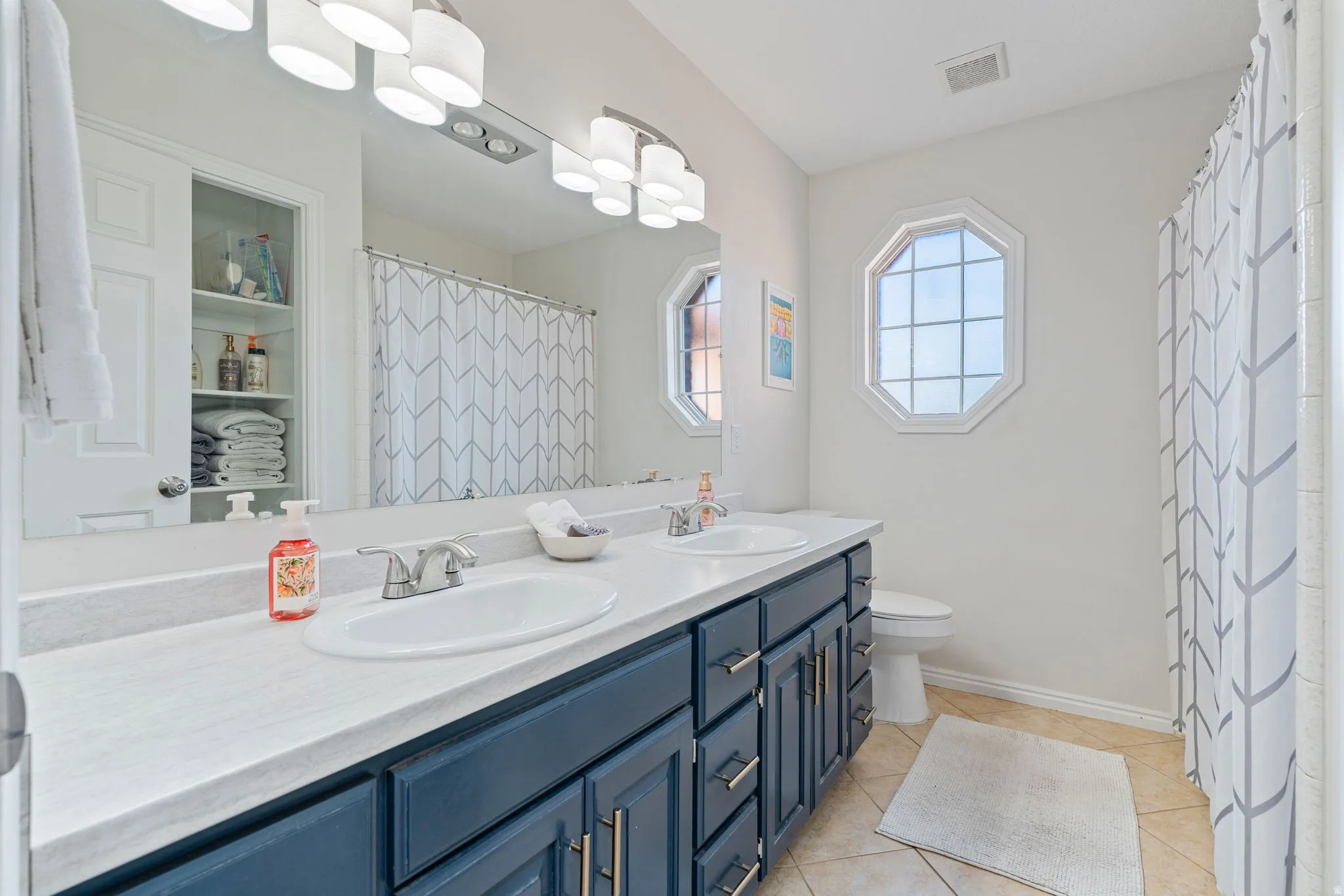Bathroom featuring a double vanity with a white countertop and blue cabinetry, dual undermount sinks, and a large wall-mounted mirror