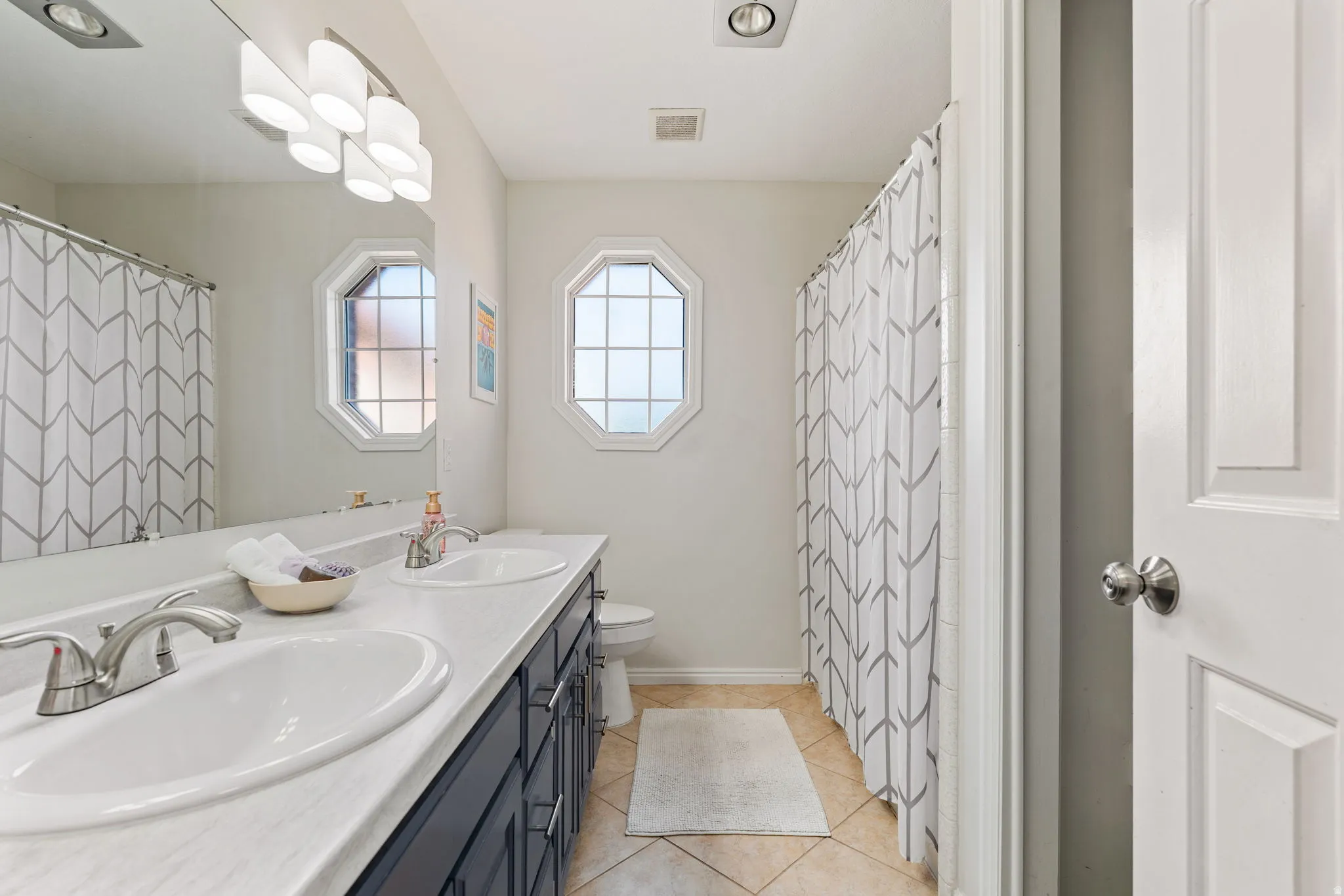 Bathroom featuring a dual vanity with undermount sinks, brushed nickel faucets, and a light-toned countertop