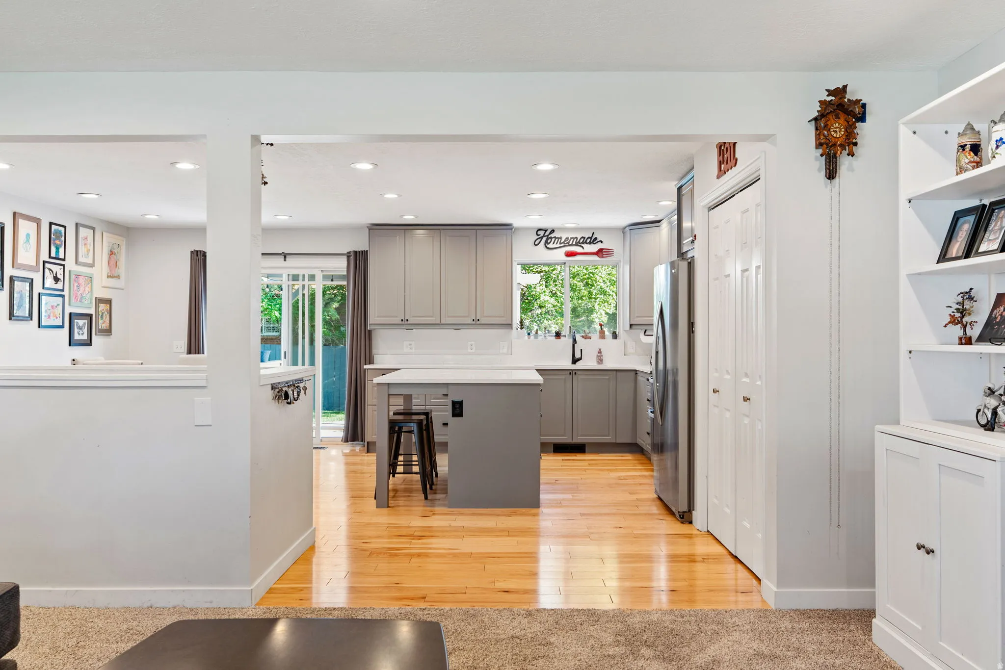 Modern kitchen featuring light gray cabinetry, stainless steel appliances, a center island with seating, and a white subway tile backsplash