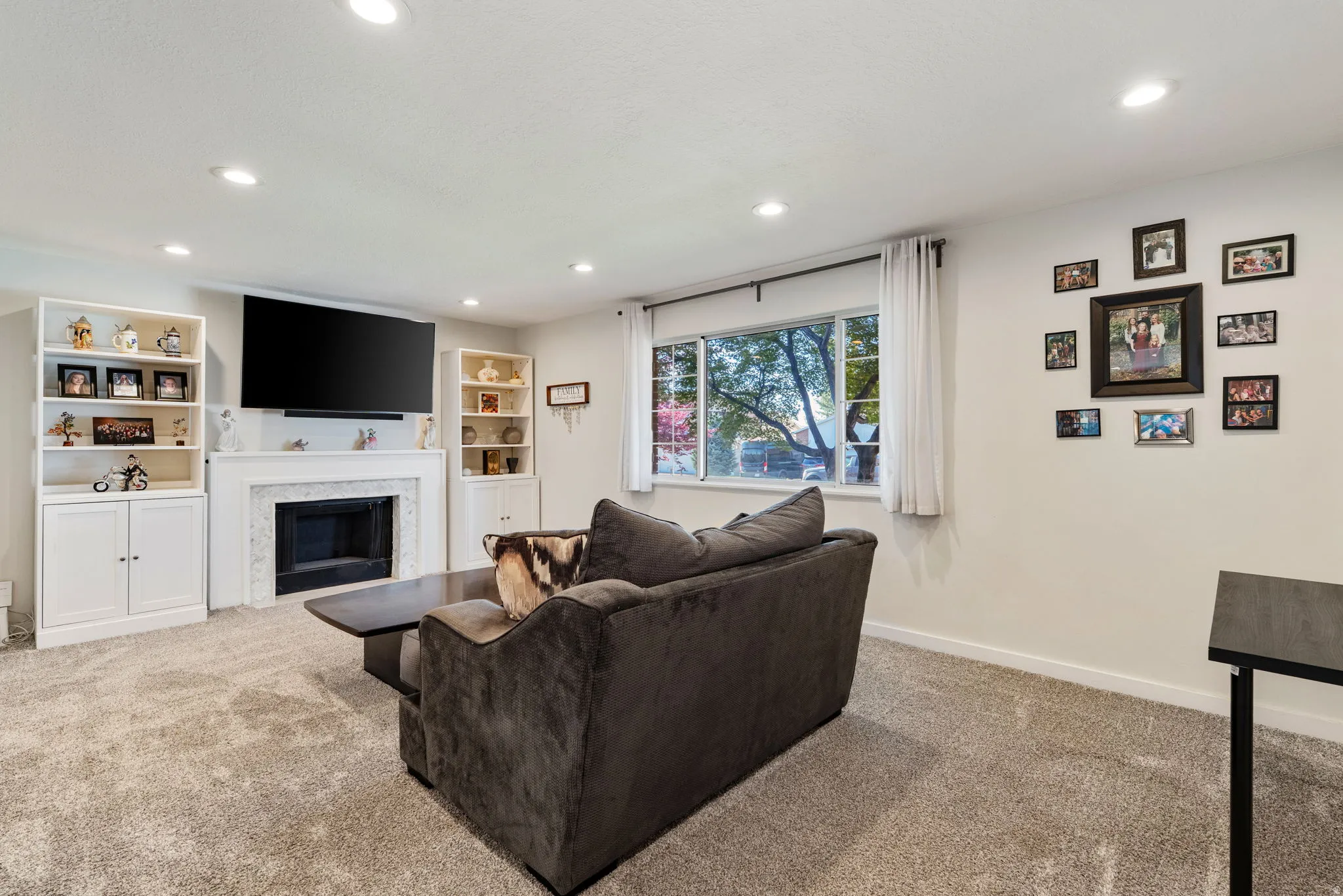 Living area featuring a fireplace with a white mantel, built-in shelving, recessed lighting, and a large window