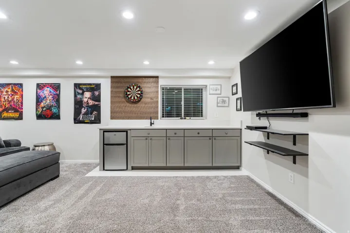 Entertainment space featuring a built-in wet bar with a compact refrigerator, a wall-mounted television, and recessed lighting