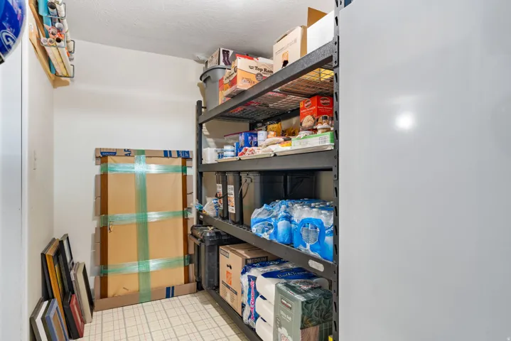 Dedicated storage area featuring utility shelving, a built-in overhead storage rack, and tiled flooring