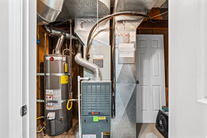 Utility closet featuring a water heater, furnace, and extensive ductwork