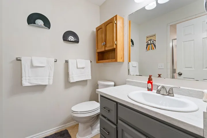 Bathroom featuring a gray vanity with an integrated sink, laminate countertop, and wood-finish cabinetry