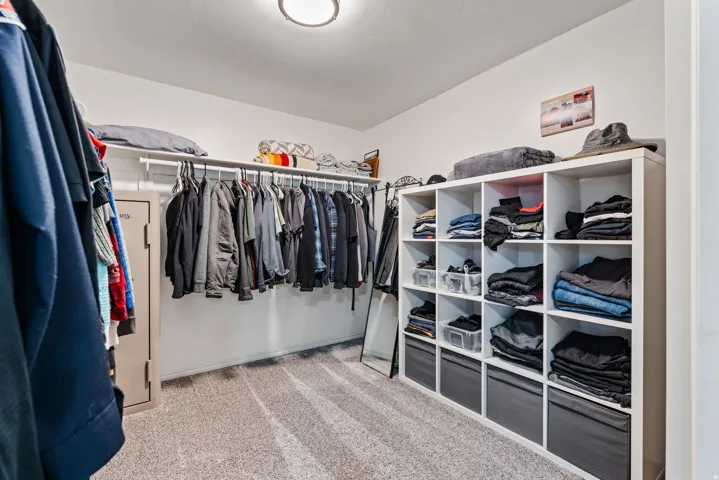 Walk-in closet featuring wall-mounted clothing rods, overhead shelving, and a large cubby storage unit