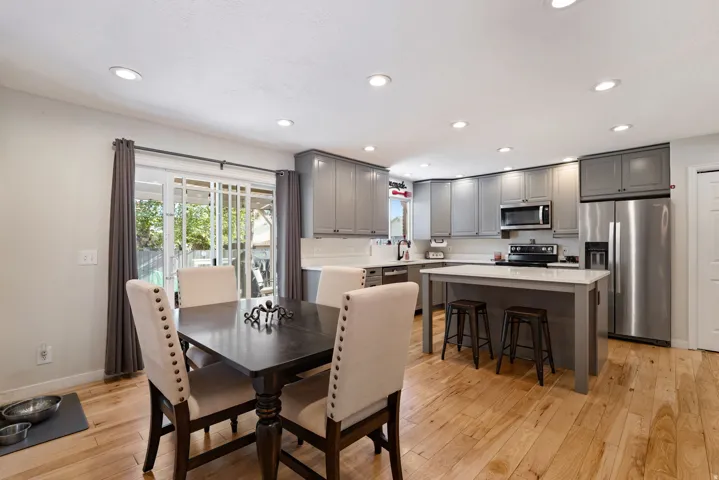 Open-concept kitchen featuring wood-finish flooring, recessed lighting, gray cabinetry, white countertops, and a full suite of stainless steel appliances