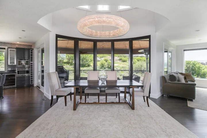 Dining area featuring dark wood-finish flooring, a large area rug, and a circular chandelier