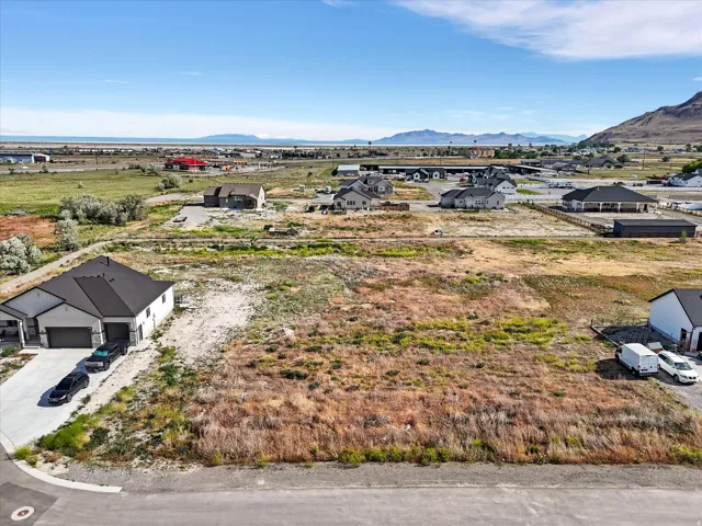 Expansive vacant land parcel featuring a clear, level building site with road frontage and mountain backdrop